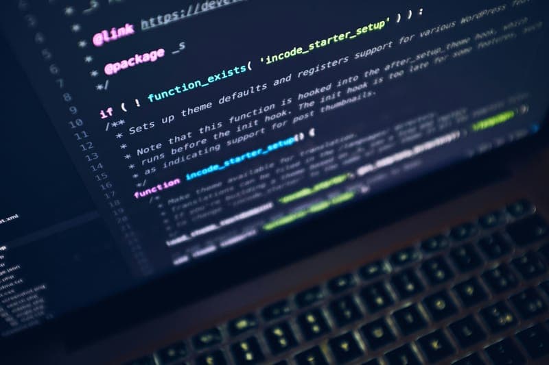 Lines of code on a laptop screen in a dark room