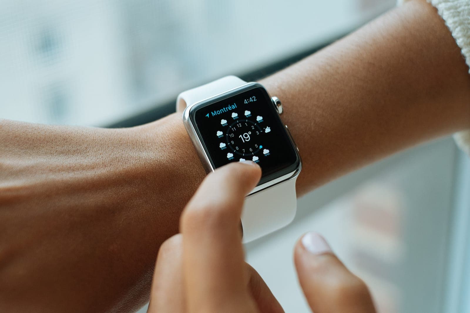 A hand tapping the face of a smartwatch on a wrist