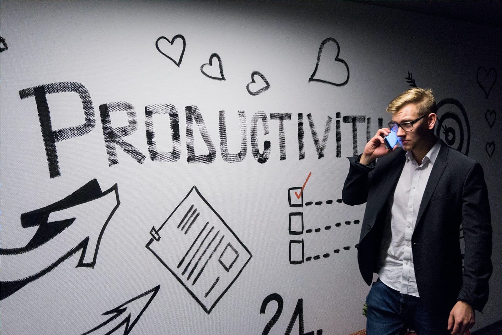 A man in a suit on the phone in front of a wall drawn with the word Productivity