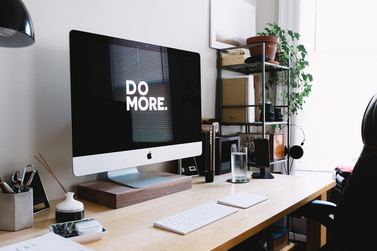 A desk with a large monitor showing the words Do More
