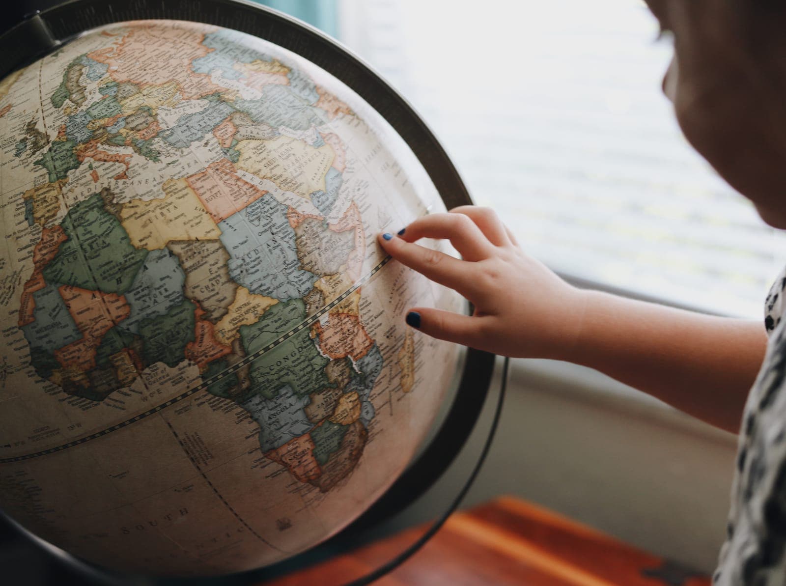 A child's hand pointing at a globe