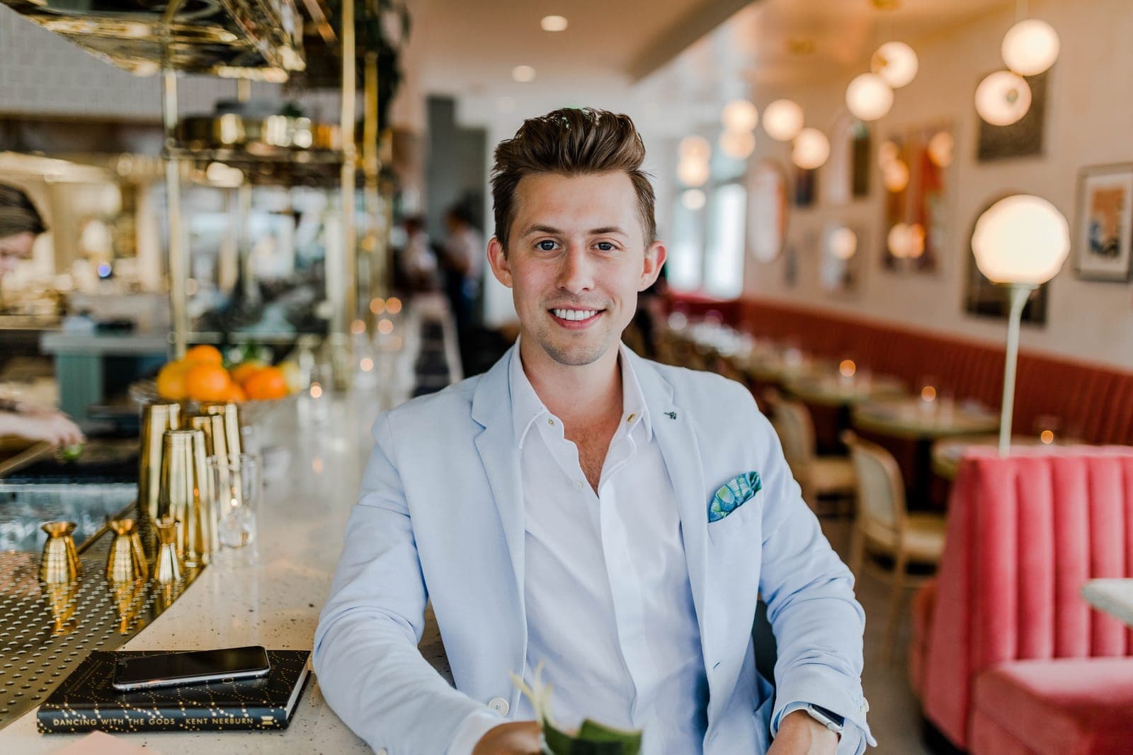 A smiling man in a light blazer sitting in a restaurant
