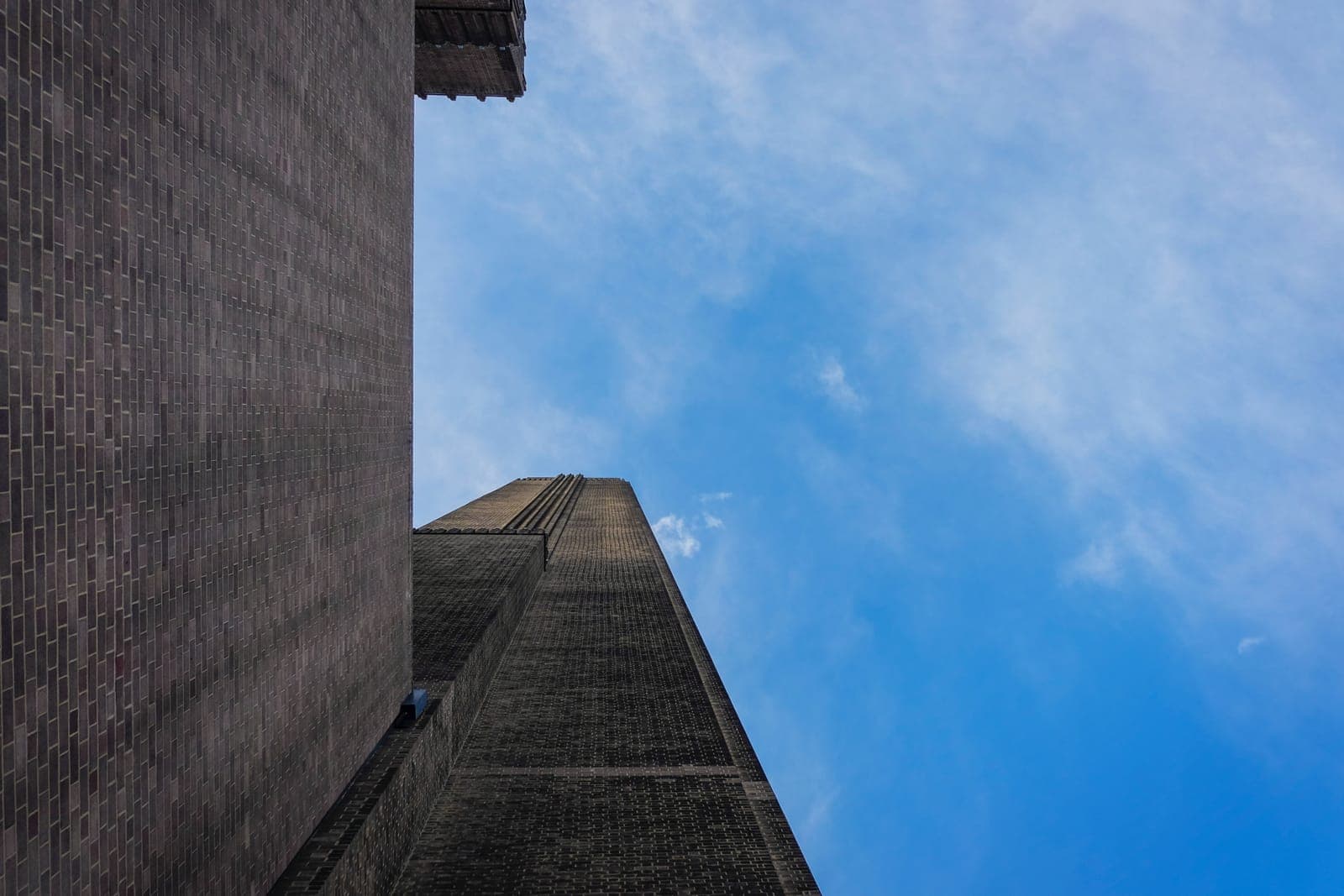 Looking up at a tall dark building against a blue sky